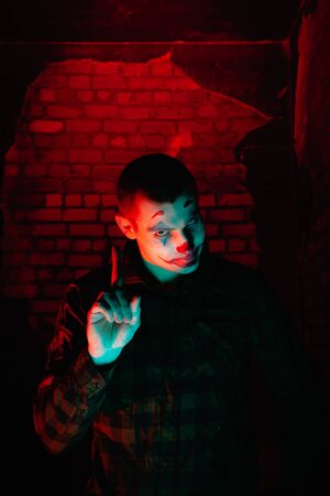 Close-up portrait of a joker man. Stock photo makeup joker in a horror room.