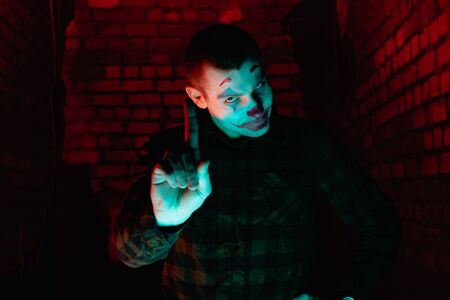 Close-up portrait of a joker man. Stock photo makeup joker in a horror room.