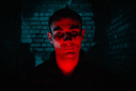 Close-up portrait of a joker man. Stock photo makeup joker in a horror room.