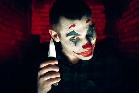 Close-up portrait of a joker man. Stock photo makeup joker in a horror room.の写真素材