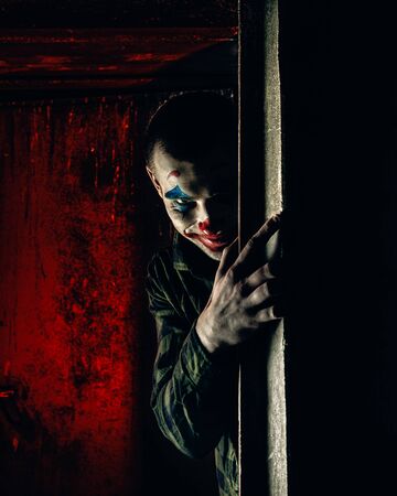 Close-up portrait of a joker man. Stock photo makeup joker in a horror room.の写真素材