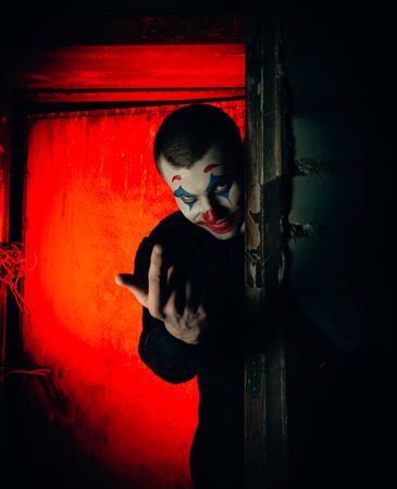 Close-up portrait of a joker man. Stock photo makeup joker in a horror room.の写真素材