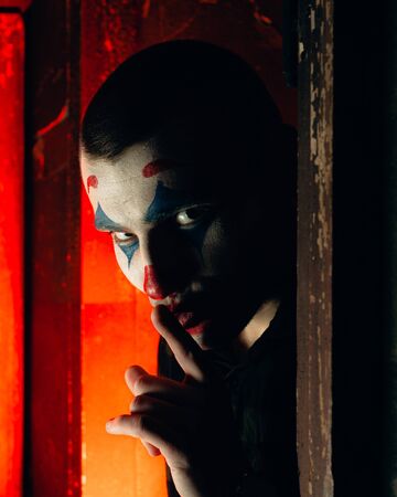 Close-up portrait of a joker man. Stock photo makeup joker in a horror room.の写真素材