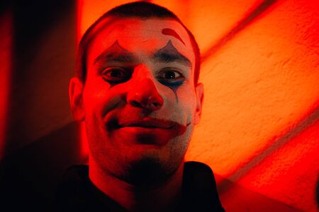 Close-up portrait of a joker man. Stock photo makeup joker in a horror room.