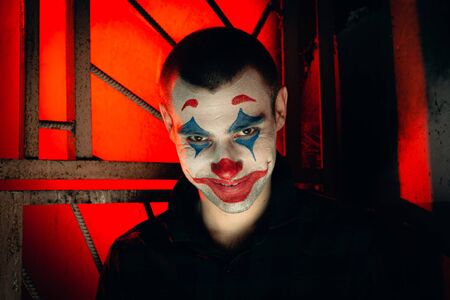 Close-up portrait of a joker man. Stock photo makeup joker in a horror room.