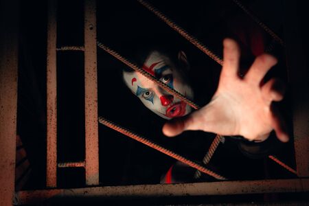 Close-up portrait of a joker man. Stock photo makeup joker in a horror room.の写真素材