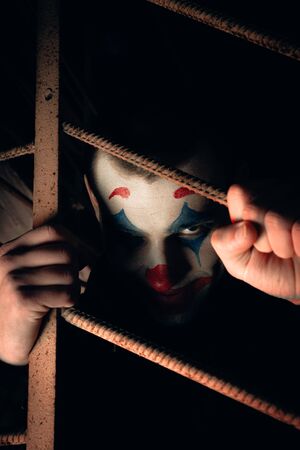 Close-up portrait of a joker man. Stock photo makeup joker in a horror room.の写真素材