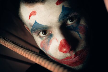 Close-up portrait of a joker man. Stock photo makeup joker in a horror room.
