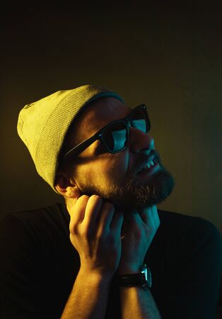 Portrait of a hipster guy with color light. Hipster face portrait in studio.
