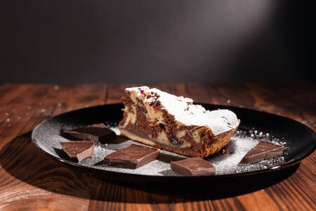 Rustic chocolate cake sprinkled with icing sugar. Chocolate cake on a wooden table.の写真素材