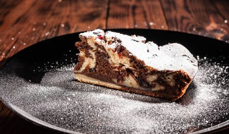 Rustic chocolate cake sprinkled with icing sugar. Chocolate cake on a wooden table.の写真素材