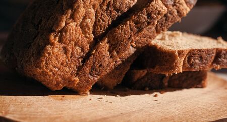 Sliced â€‹â€‹black rye bread on a wooden board. Brick-shaped bread.