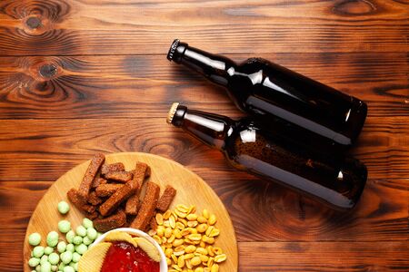 Beer in a bottle with dry salty snack, on a wooden table with free space.の写真素材