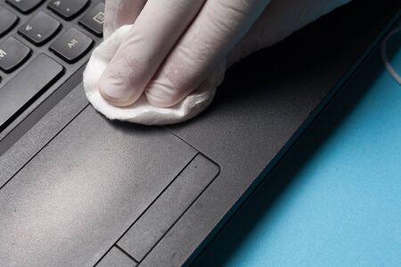 Close-up of disinfection cleaning a laptop in white gloves. Prevention of coronavirus infection.