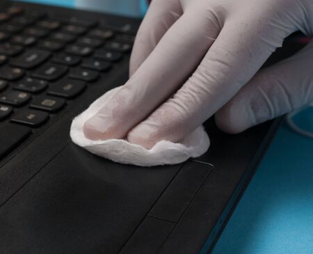 Close-up of disinfection cleaning a laptop in white gloves. Prevention of coronavirus infection.の写真素材