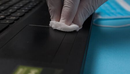 Close-up of disinfection cleaning a laptop in white gloves. Prevention of coronavirus infection.