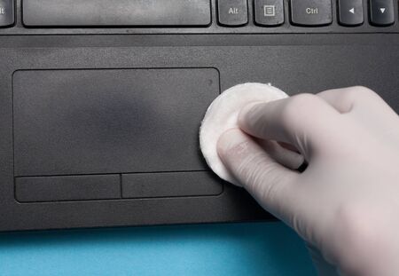 Close-up of disinfection cleaning a laptop in white gloves. Prevention of coronavirus infection.