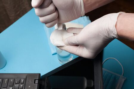 Close-up of disinfection cleaning a laptop in white gloves. Prevention of coronavirus infection.