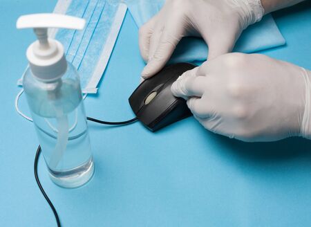 Close-up of disinfection, cleaning of a white-gloved computer mouse. Prevention of coronavirus...