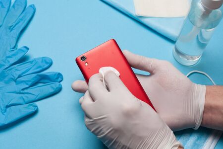 Close-up of disinfection, cleaning smartphone in white gloves. Prevention of coronavirus infection.Close-up of disinfection, cleaning smartphone in white gloves. Prevention of coronavirus infection.の写真素材