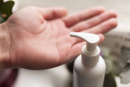 Close-up of a hand sanitizer. Prevention and hygiene of coronavirus and epidemic during quarantine. Men's hands close-up.の写真素材