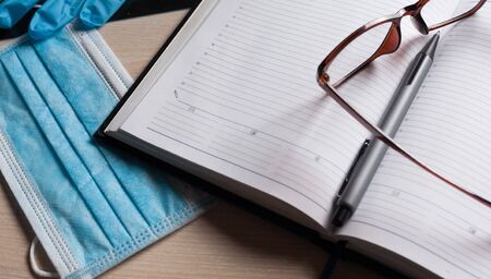Empty notepad on hospital desk surrounded by medical equipment. Top view, flat lay composition. Notepad, mask, sanitizer and pen on table. Concept of virus 2019-nCoV, coronavirus, illness. Medical check up.の写真素材