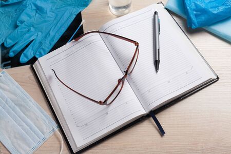 Empty notepad on hospital desk surrounded by medical equipment. Top view, flat lay composition. Notepad, mask, sanitizer and pen on table. Concept of virus 2019-nCoV, coronavirus, illness. Medical check up.の写真素材