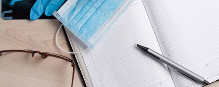 Empty notepad on hospital desk surrounded by medical equipment. Top view, flat lay composition. Notepad, mask, sanitizer and pen on table. Concept of virus 2019-nCoV, coronavirus, illness. Medical check up.の写真素材