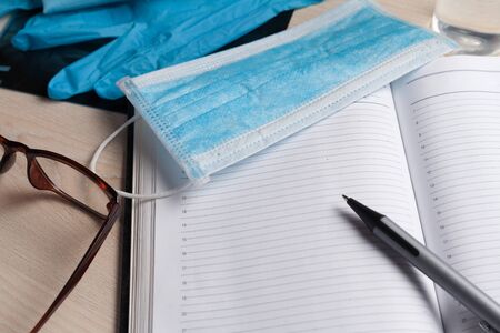 Empty notepad on hospital desk surrounded by medical equipment. Top view, flat lay composition. Notepad, mask, sanitizer and pen on table. Concept of virus 2019-nCoV, coronavirus, illness. Medical check up.の写真素材