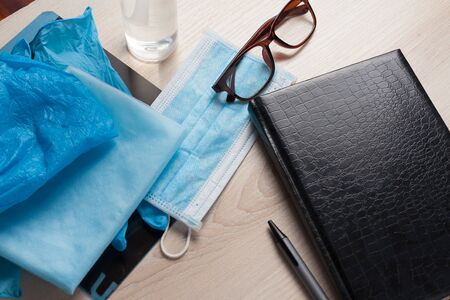 Empty notepad on hospital desk surrounded by medical equipment. Top view, flat lay composition. Notepad, mask, sanitizer and pen on table. Concept of virus 2019-nCoV, coronavirus, illness. Medical check up.の写真素材