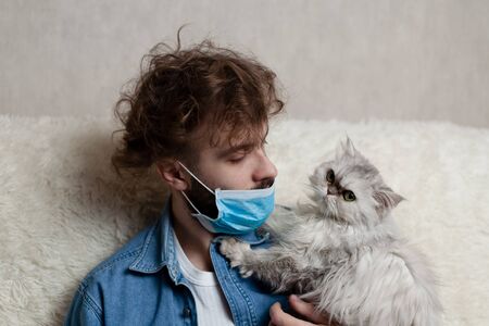 A man with his pet is sitting on a sofa at home. Quarantine coronavirus.の写真素材