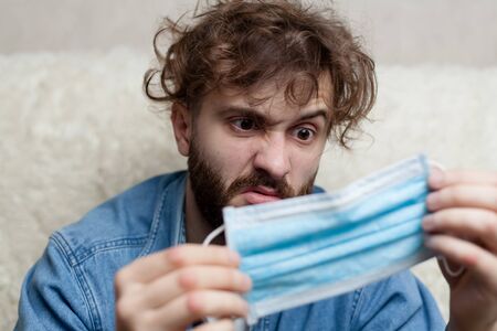 Portrait of a guy with a medical mask that stinks. Bad smell of a rotten medical mask. The concept...