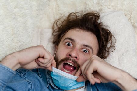 Lone guy at home in quarantine. Staying at home makes you sad and crazy. Home isolation and its consequences for the psychological health of a person.の写真素材