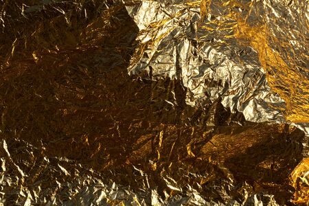 Texture of a thin crumpled sheet of foil. Crumpled foil background. Stock photo foil. Gold chrome...