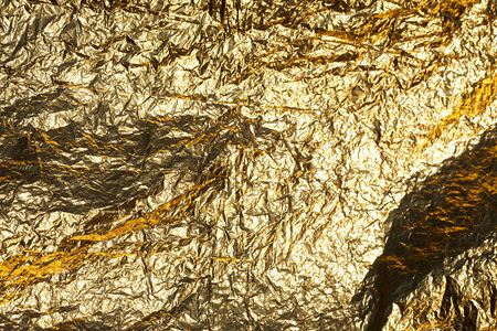 Texture of a thin crumpled sheet of foil. Crumpled foil background. Stock photo foil. Gold chrome...