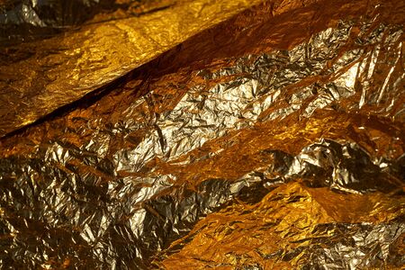 Texture of a thin crumpled sheet of foil. Crumpled foil background. Stock photo foil. Gold chrome...