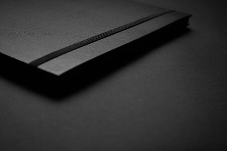 Blank black notebook on a black table, mockup photo. Blank black cover template with copy space for...