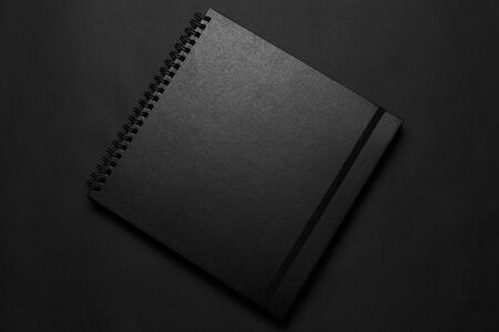 Blank black notebook on a black table, mockup photo. Blank black cover template with copy space for...