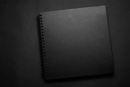Blank black notebook on a black table, mockup photo. Blank black cover template with copy space for...