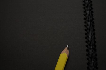 Blank black notebook on a black table, mockup photo. Blank black cover template with copy space for design. Black on black, minimal design concept.の写真素材