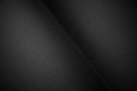 Blank black notebook on a black table, mockup photo. Blank black cover template with copy space for design. Black on black, minimal design concept.の写真素材