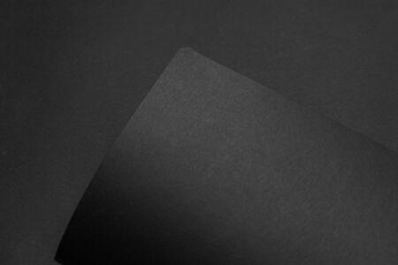 Blank black notebook on a black table, mockup photo. Blank black cover template with copy space for design. Black on black, minimal design concept.の写真素材