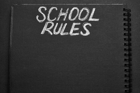 School rules word written on a notepad with blank space. Blank black notepad background.の写真素材