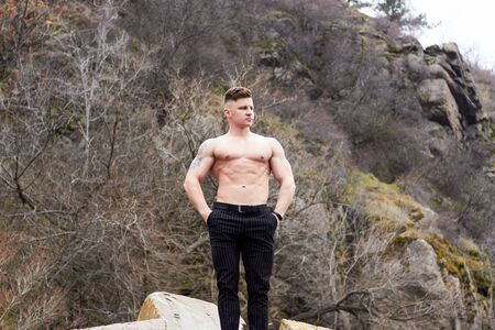 Attractive young guy demonstrates muscular torso outdoors. Beautiful physique. Fitness and lifestyle concept. Pronounced muscles of the press. Athletic physique.の写真素材
