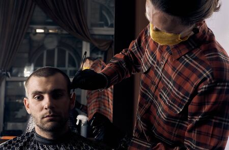 Male hairdresser in a protective mask and gloves, dressed in casual clothes. Client without a mask....