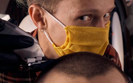 Male hairdresser in a protective mask and gloves, dressed in casual clothes. Client without a mask....