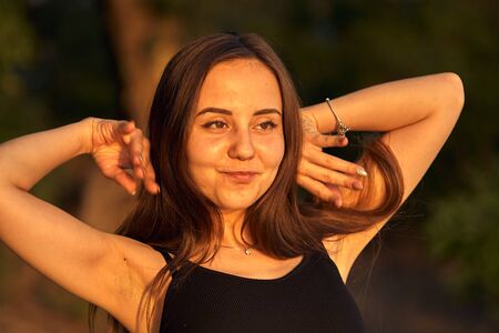 Beautiful girl on the nature near the green shore. Enjoys the setting sun. The concept of outdoor...