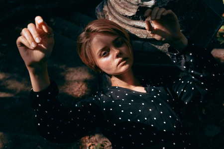 Fashionable portrait of a girl in a dress with polka dots on a background of nature and old architecture.の写真素材