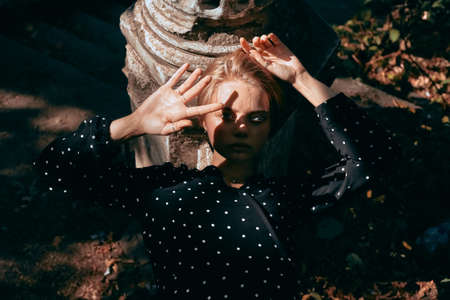 Fashionable portrait of a girl in a dress with polka dots on a background of nature and old...