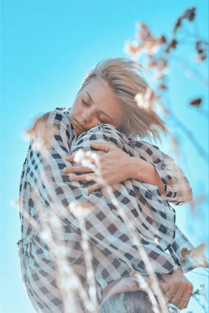 Cute fashionable girl in a plaid dress posing against the blue sky.